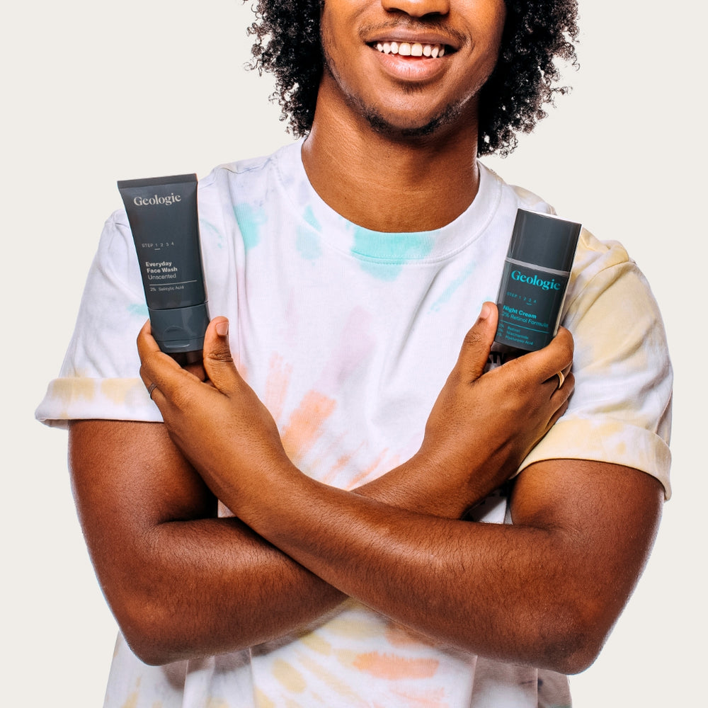 Man smiling while holding two Geologie Acne Duo products with effective ingredients for a clear complexion.