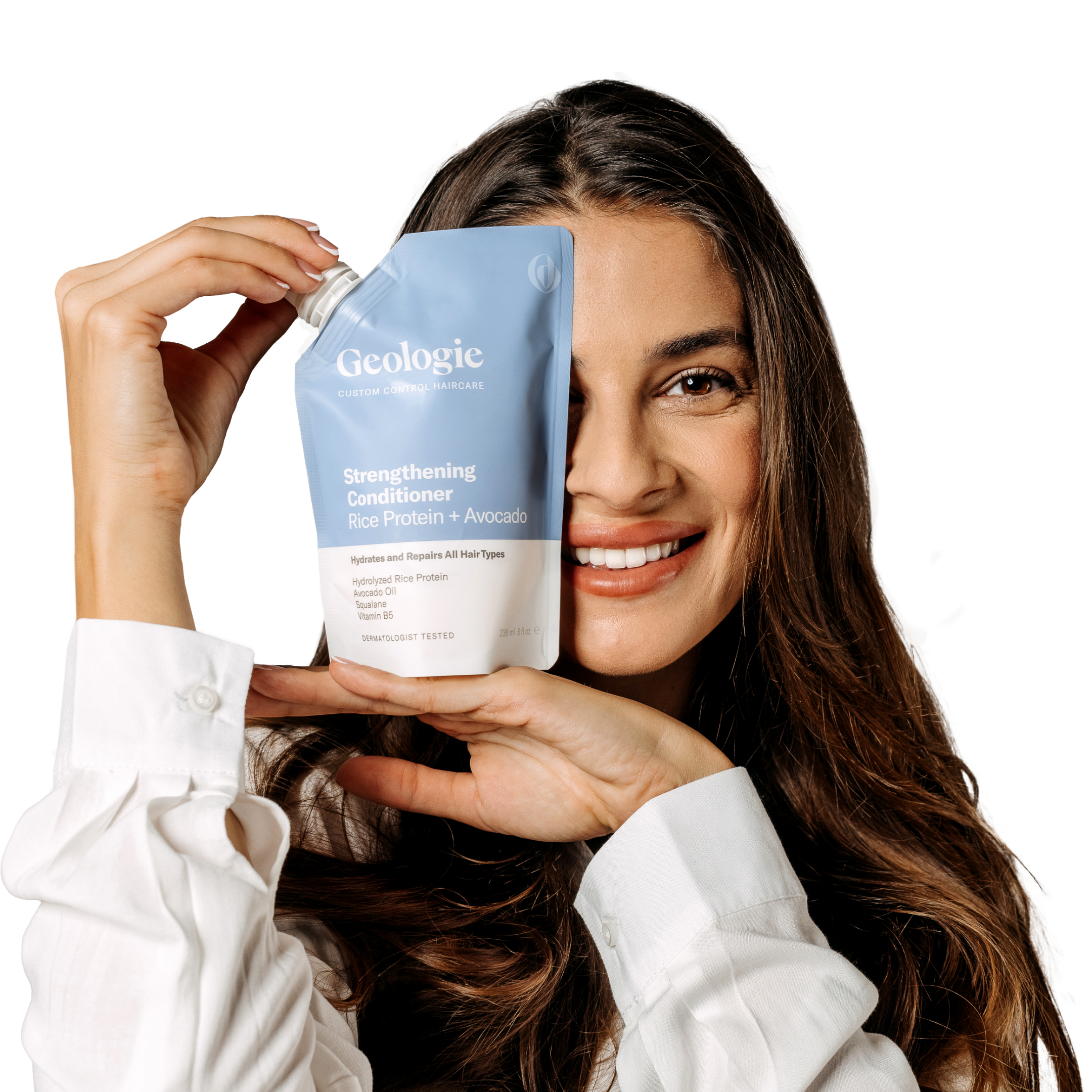 A woman smiling while holding a package of Geologie Anti-Dandruff Haircare Set.