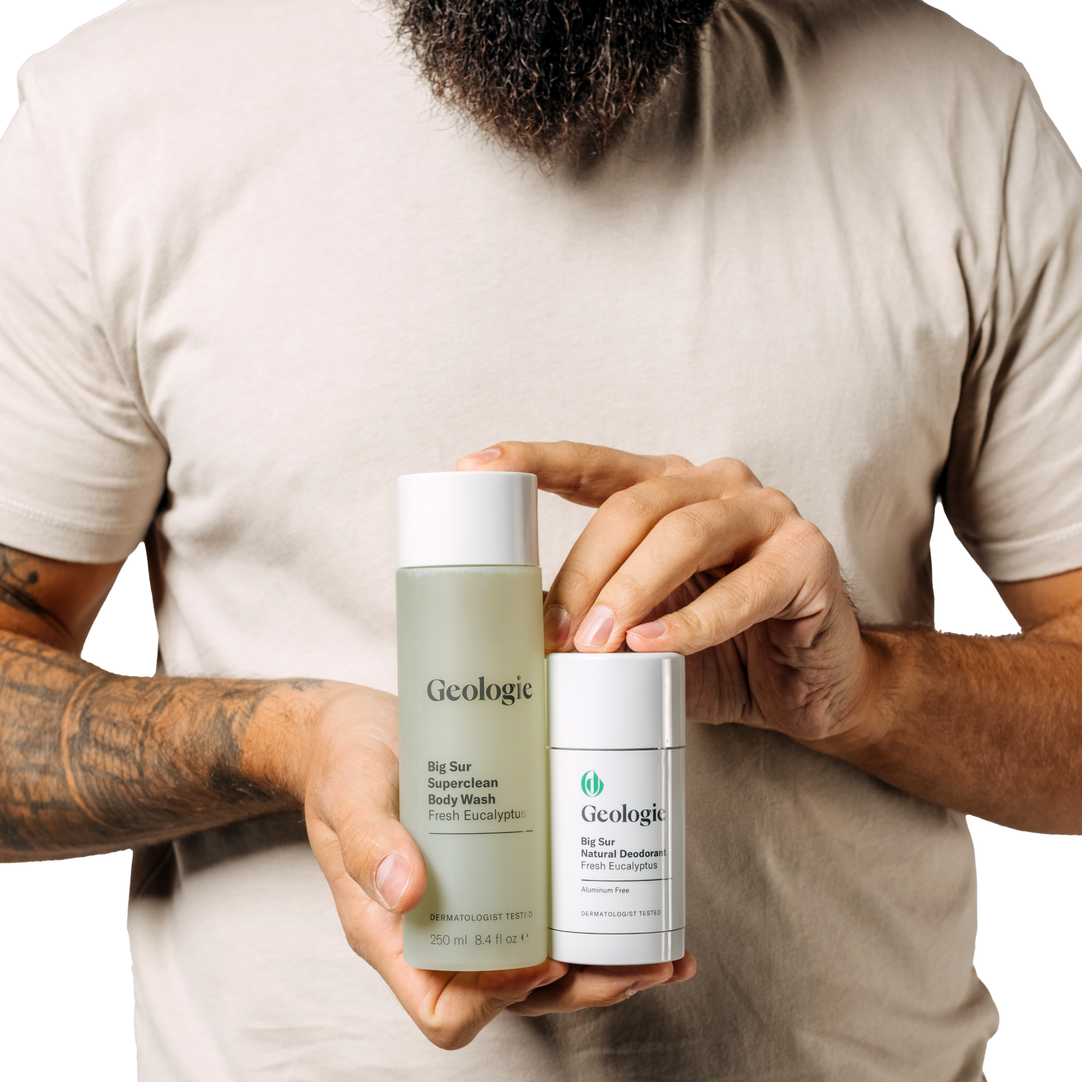 A man holding a bottle of Geologie Body Bundle, including long-lasting deodorant and luxurious body wash.