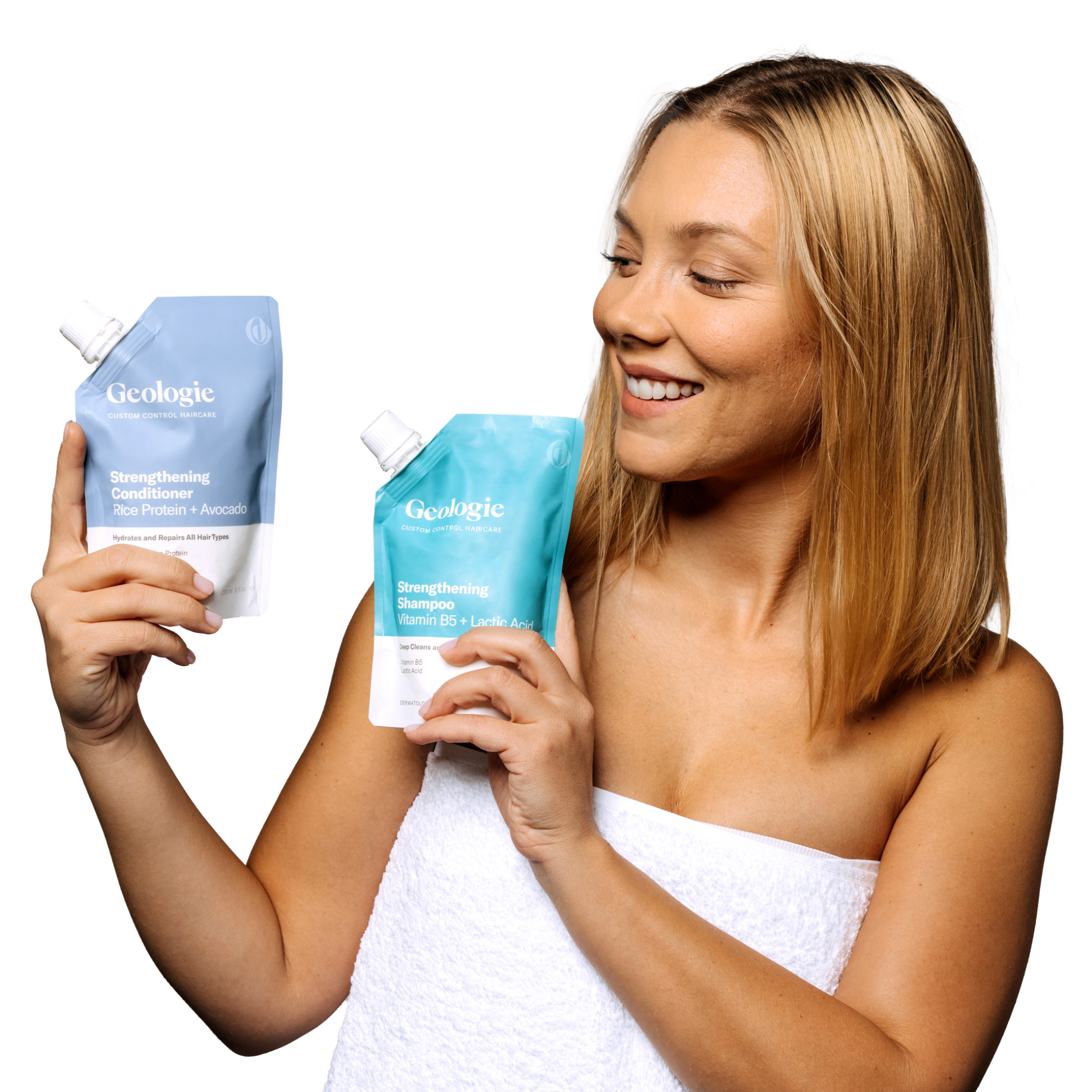 Woman smiling while holding two bottles of Geologie Shampoo + Conditioner Bundle that nourish the skin.