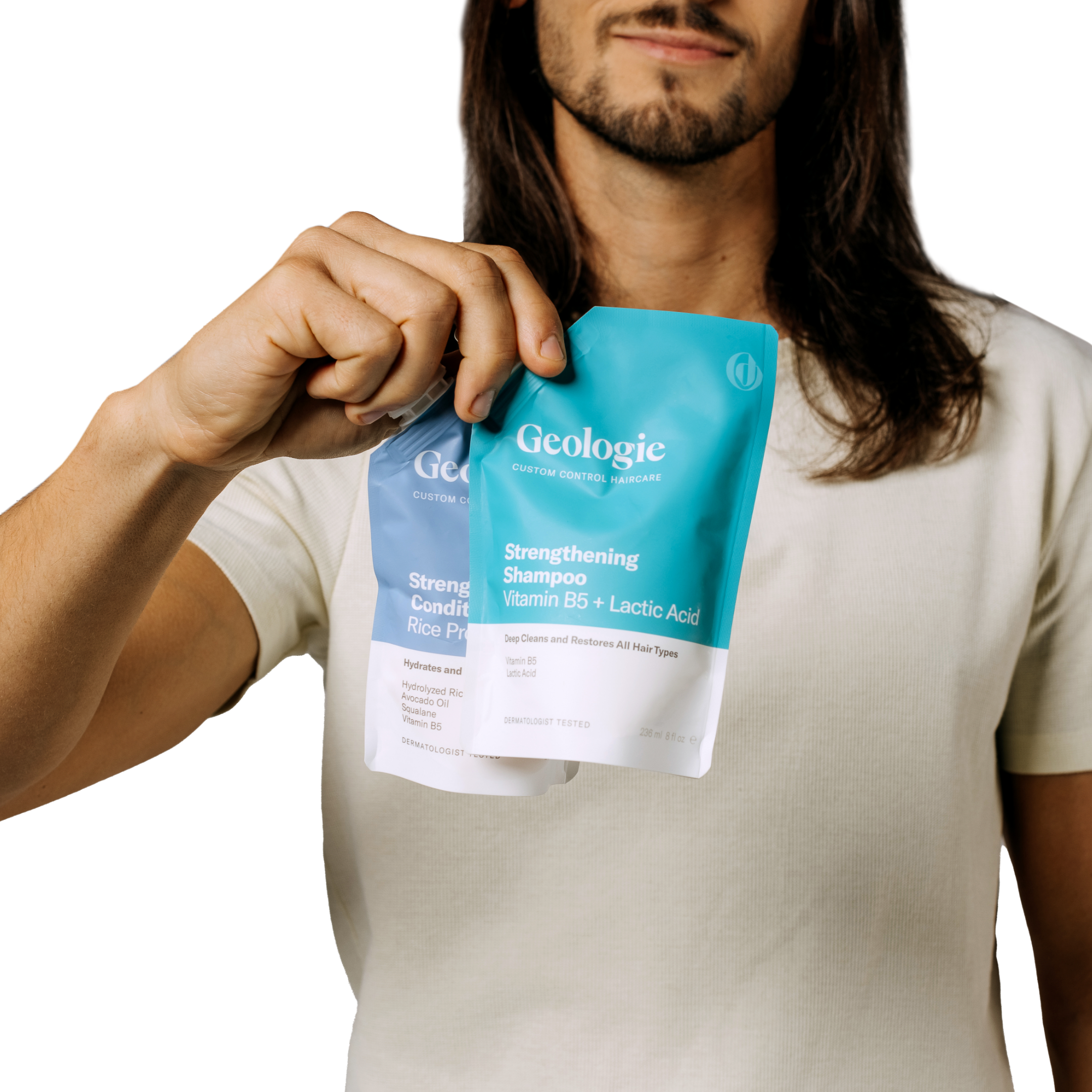 Man holding a sachet of Geologie Shampoo + Conditioner Bundle that nourishes and repairs for stronger hair.