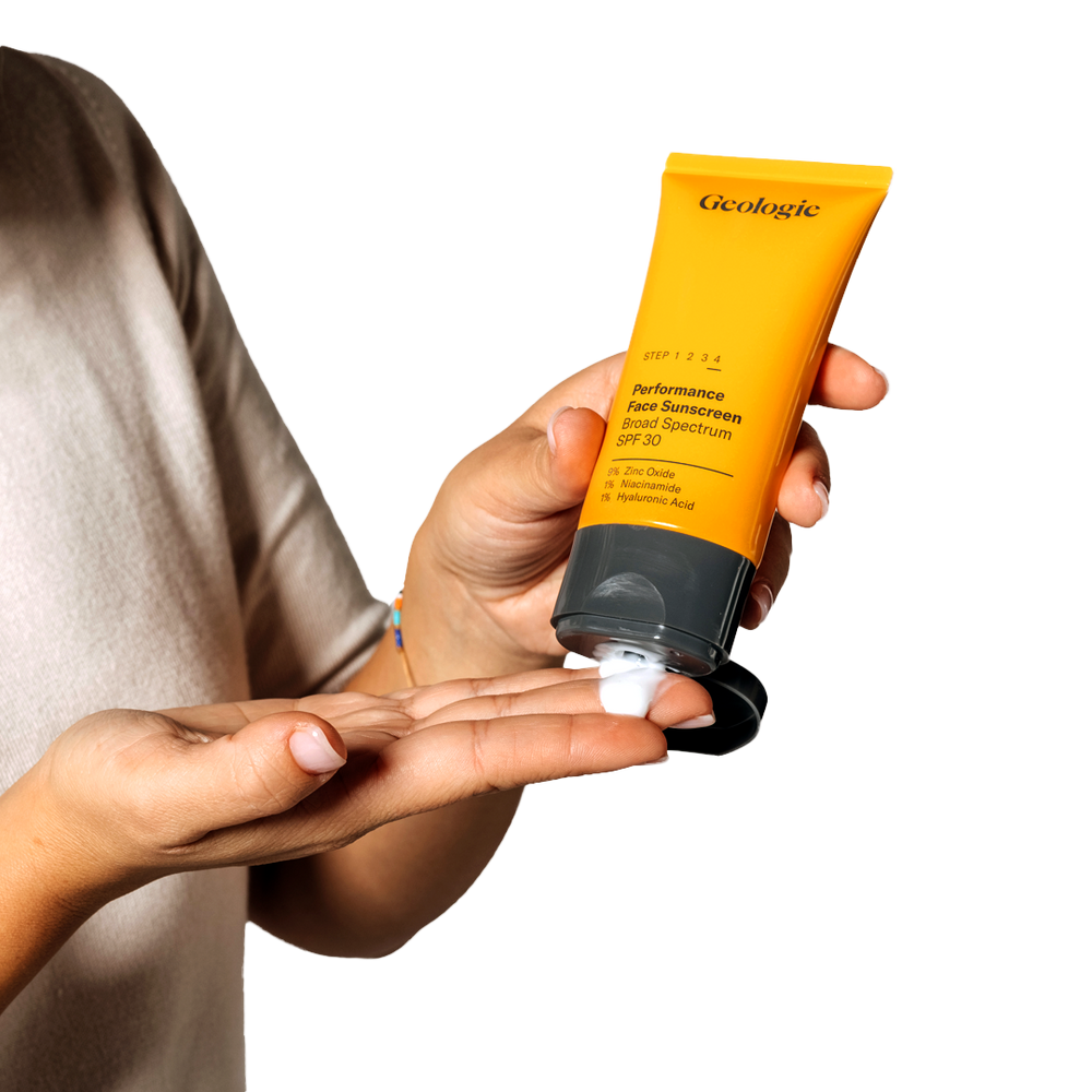 A person dispensing yellow, Geologie branded kojic acid sunscreen onto their hand from a tube.